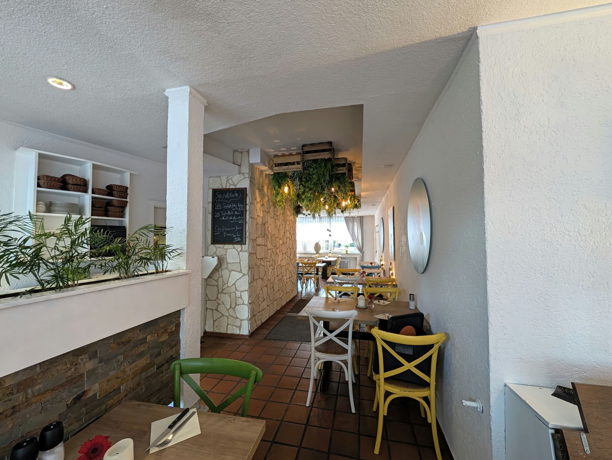 Durchgang mit Pflanzen, Kreidetafel und gelben Stühlen
